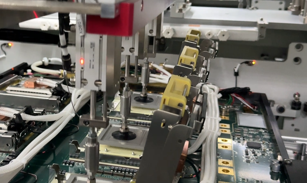 An automated assembly machine with mechanical arms pressing down on components of a circuit board.