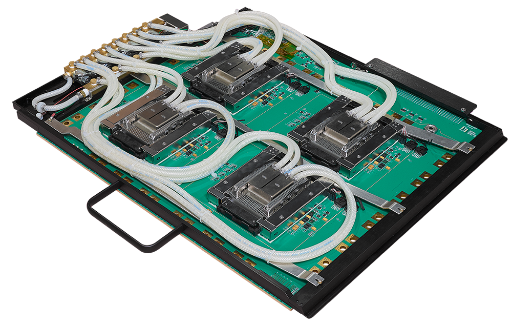 A large green circuit board featuring four processor sockets, each equipped with a liquid cooling block connected by white tubing.