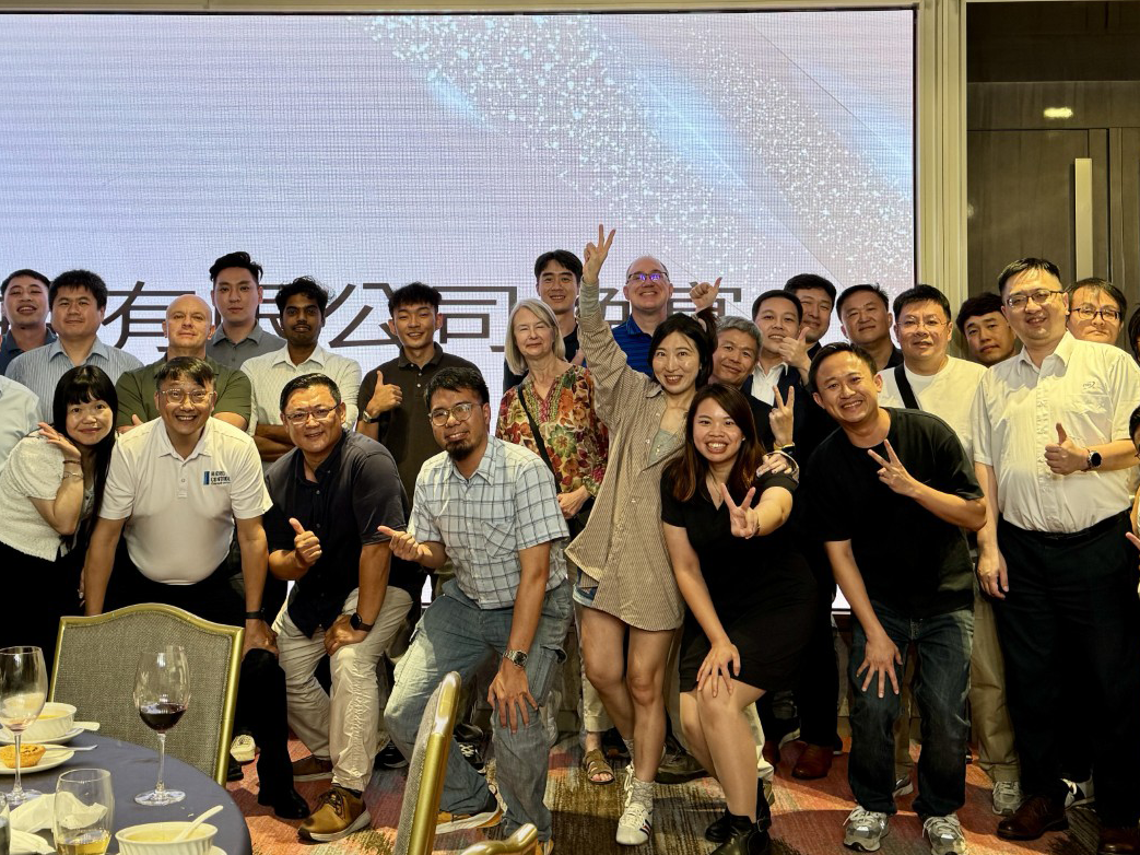A large group of people posing for a photo in front of a projection screen.